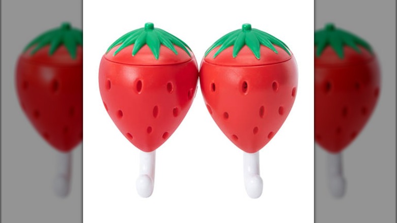 Two white plastic hooks each topped by a decorative plastic strawberry