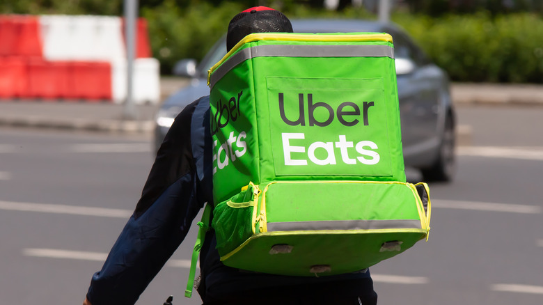 A closeup of an UberEats delivery driver on a bike with a branded backpack