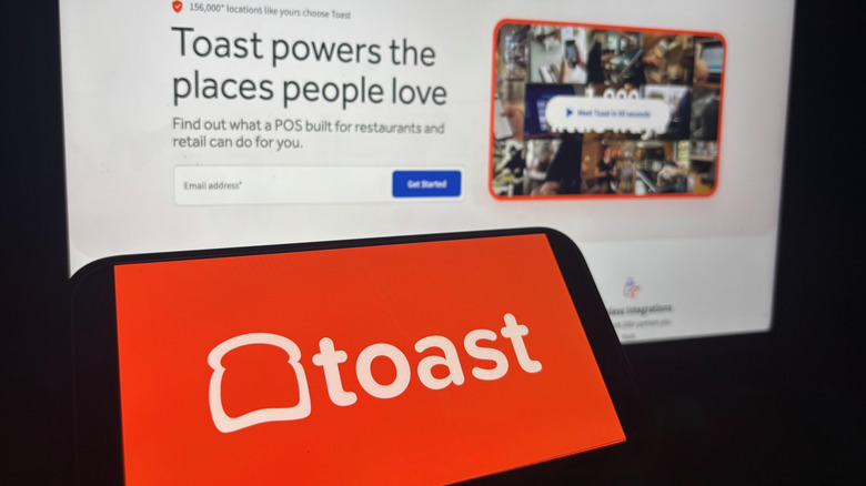 A closeup of the Toast loading screen with an iPad displaying the Toast logo in front of it