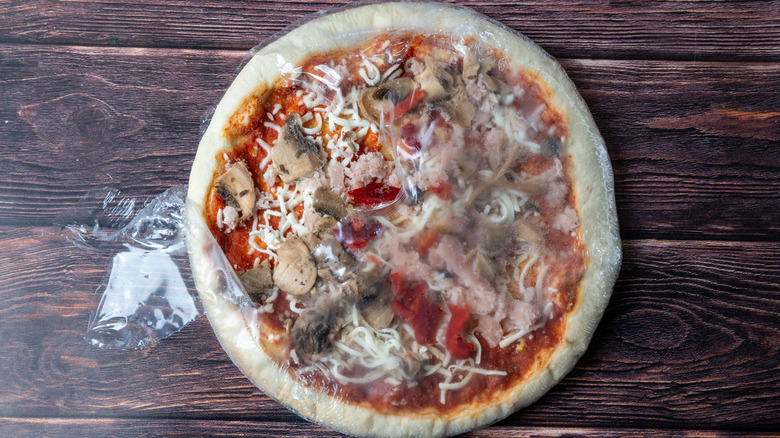 A half-unwrapped frozen pizza