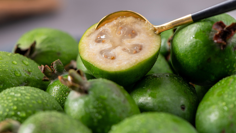 A pile of feijoa, with a halved fruit on top of them