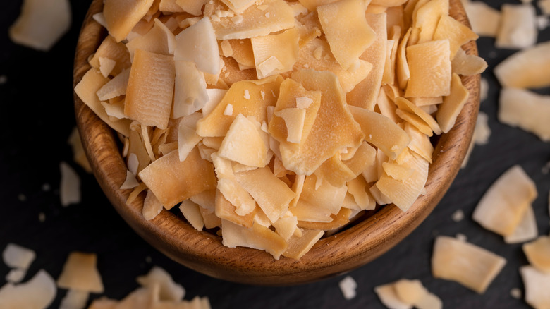 Closeup of a bowl of toasted coconut flakes on a dark tabletop