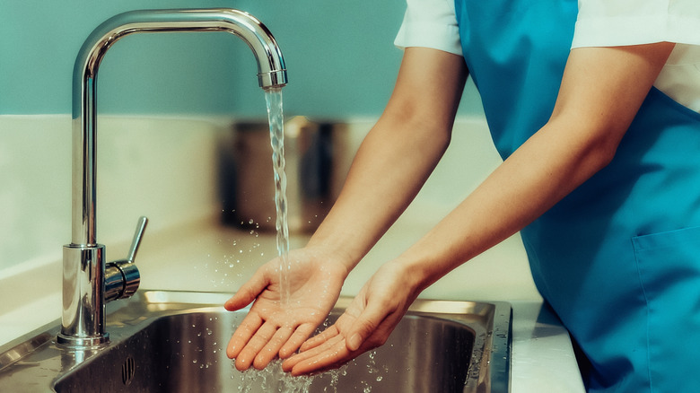 A person washes their hands in a sink