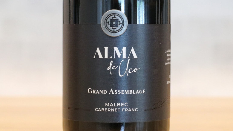 Alma de Uco Grand Assemblage bottle and close up of black label on table