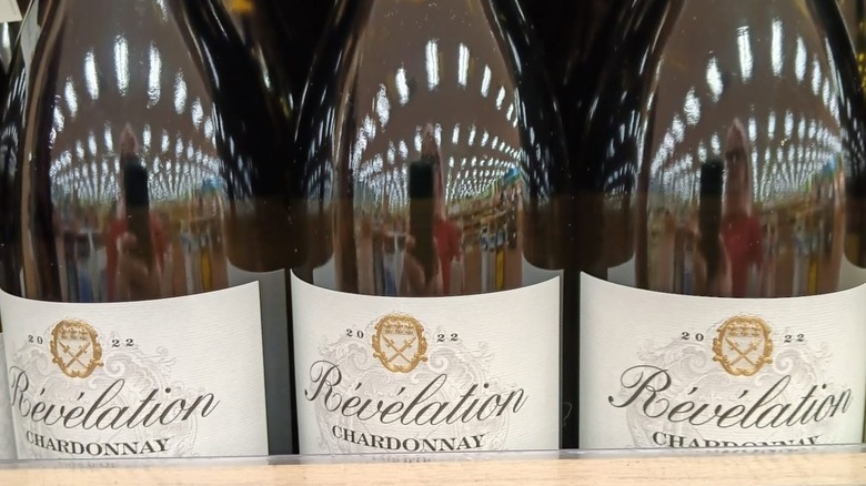 A close up of 3 Révélation Pays d'Oc Chardonnay labels and bottles on a shelf