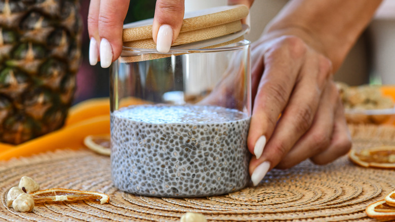 A person opening a jar of chia pudding to add toppings