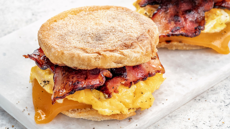 A breakfast sandwich in an English muffin with bacon and eggs