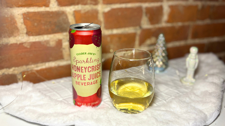 glass of juice next to a can against a brick background