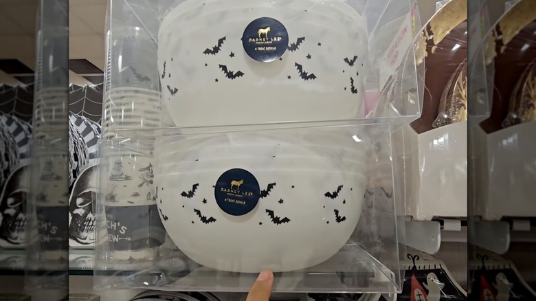 A hand pointing at two sets of four white plastic bowls with bat designs