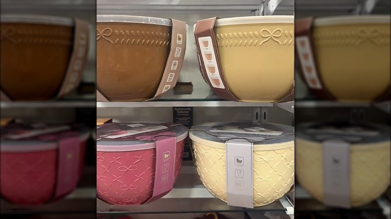 Four different colors of mixing bowl sets with a bow decoration on a HomeGoods shelf