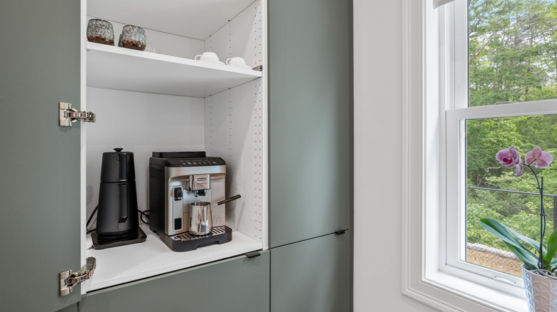 Espresso machine and electric kettle in open kitchen cabinet