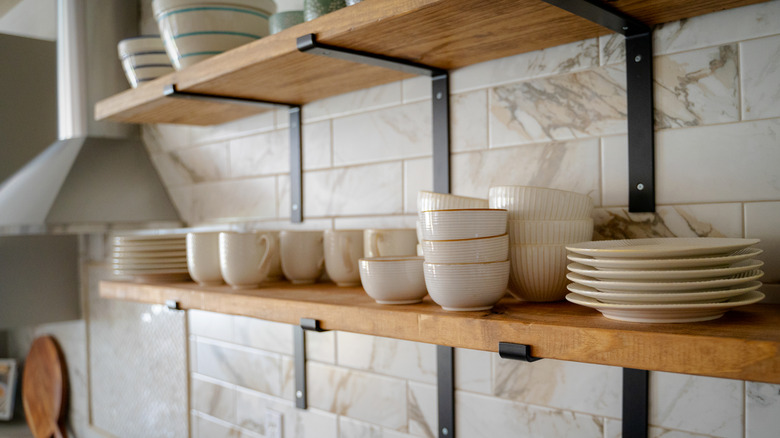 Open shelving in a kitchen, with cups, bowls, and plates arranged on the shelves