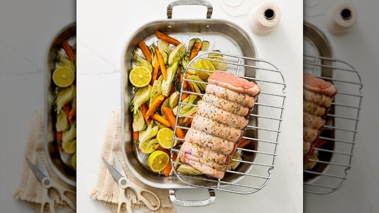 Roasting pan with veggies and a beef roast on the rack