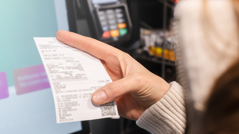 Woman inspecting receipt at self-checkout