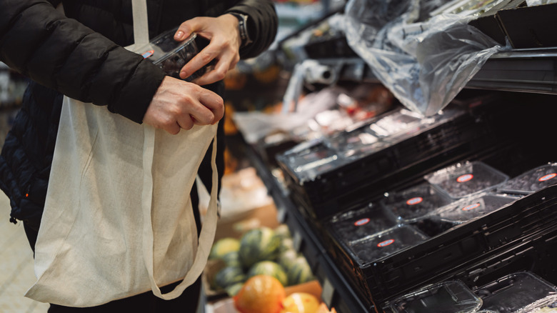 Man putting produce in reusable bag