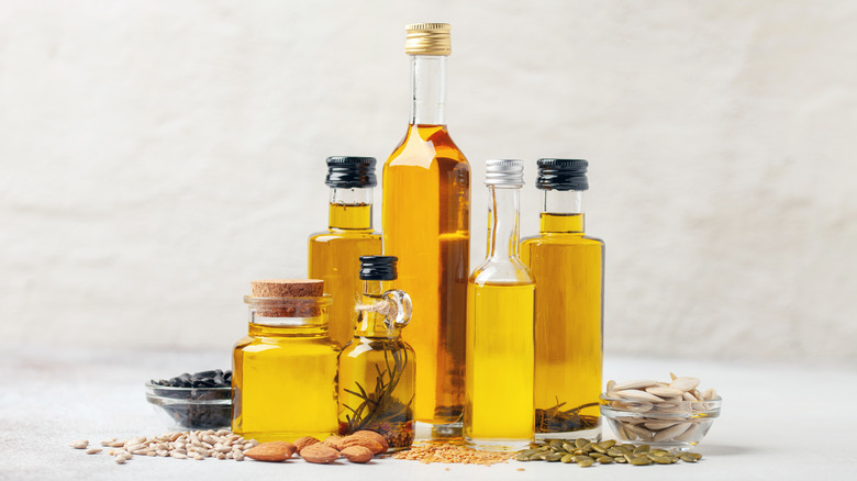 Various bottles of oil arranged together surrounded by whole spices