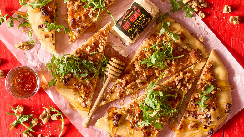 Hot honey goat milk cheese next to pizza with honey