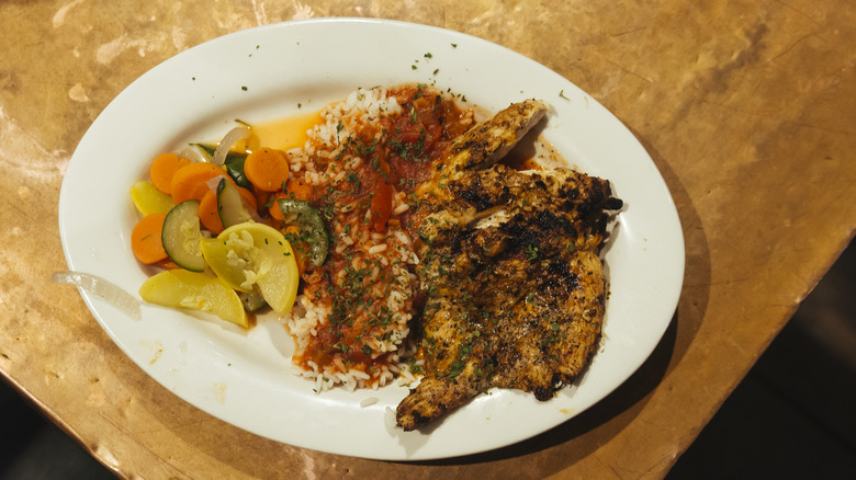 A plate of blackened chicken with rice and vegetables