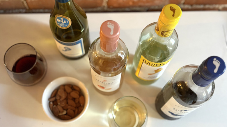 Four wine glasses are pouring into by a bottle of wine against a blurry background