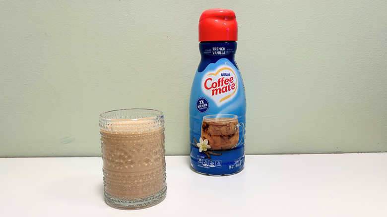 A cup of coffee next to a container of Coffee Mate French Vanilla Coffee Creamer