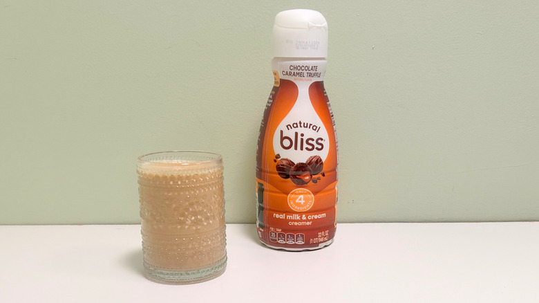 A cup of coffee next to a bottle of Coffee Mate natural Bliss Chocolate Caramel Truffle Coffee Creamer