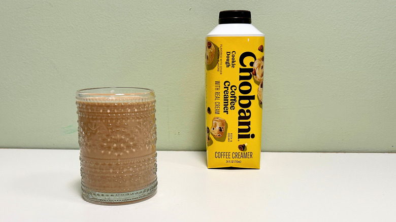 A cup of coffee next to a bottle of Chobani Cookie Dough Coffee Creamer