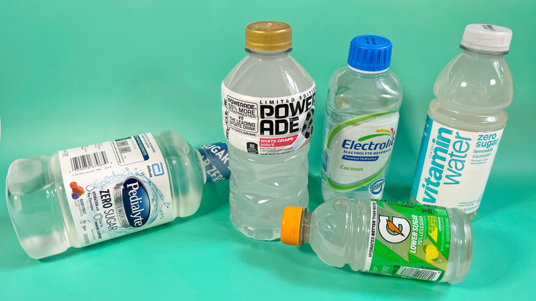 Several clear flavors of different sports drink on a teal background