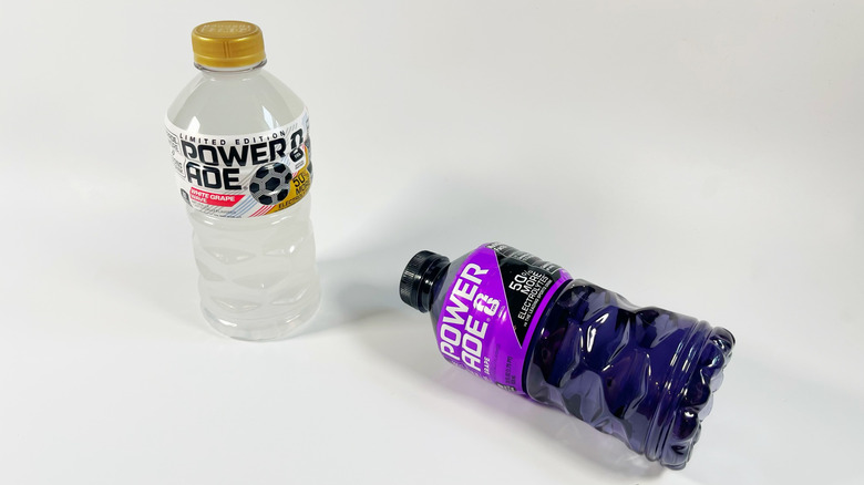 Two bottles of Powerade with one tipped over on a white background