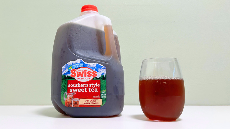 A jug of Swiss Premium Southern Style Sweet Tea next to a glass of sweet tea