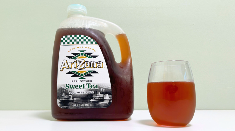A jug of AriZona Southern Style Sweet Tea next to a glass of sweet tea