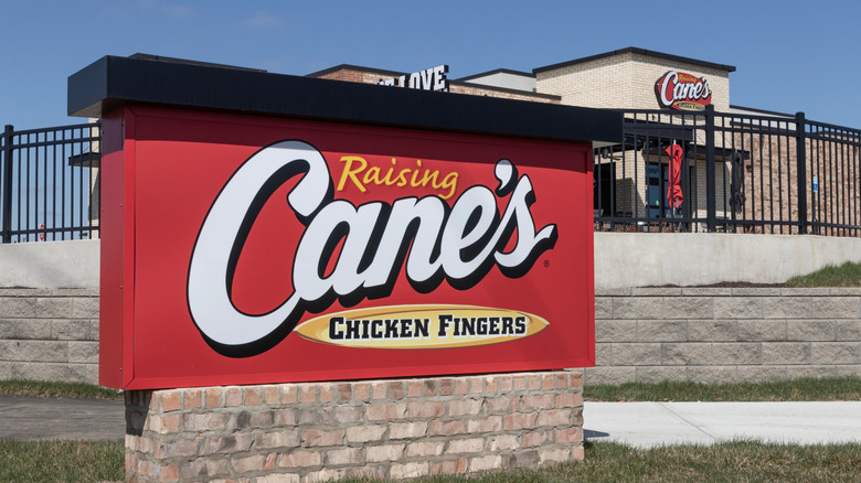 A Raising Cane's sign is seen outside one of its restaurants, against a blue sky