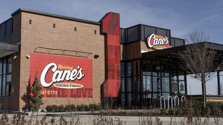 The exterior of a Raising Cane's restaurant, showing its front doors and signage prominently