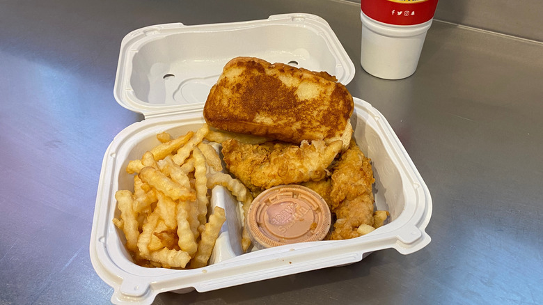 A three finger combo from Raising Cane's, with Texas toast, fries, and Cane's Sauce, served in a plastic box
