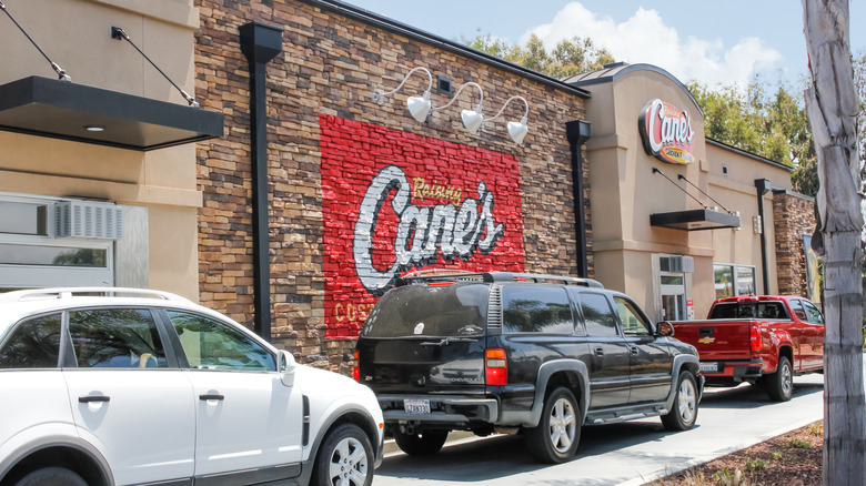 A row of cars is seen outside a Raising Cane's restaurant, waiting for its drive thru window