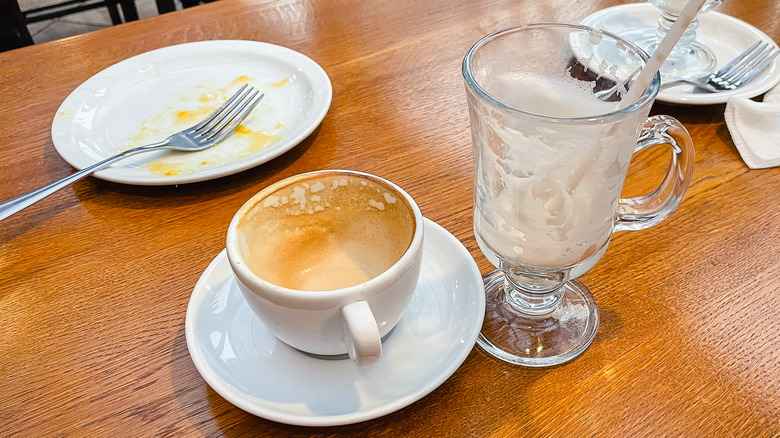 A dirty plate, coffee mug, and a glass on a wooden table