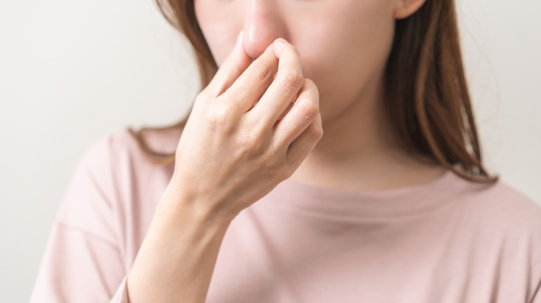 A woman holding her nose as something smells bad