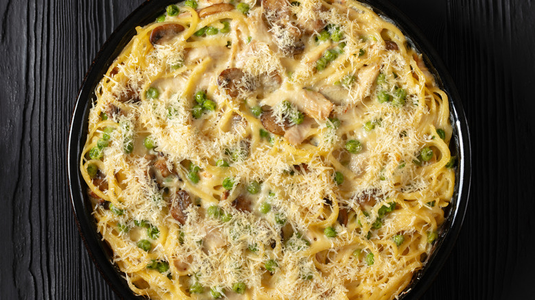 A round pan of chicken Tetrazzini, topped with sprinkled cheese