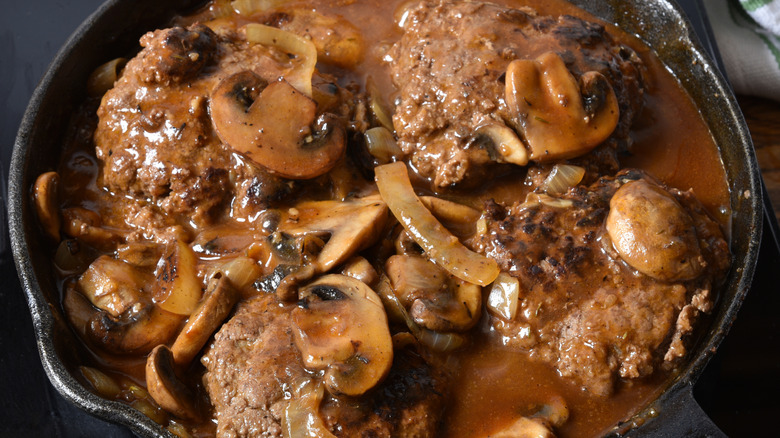 A pan of salisbury steaks with mushrooms and gravy