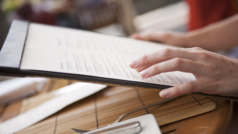 Close-up of a woman's hands holding a menu
