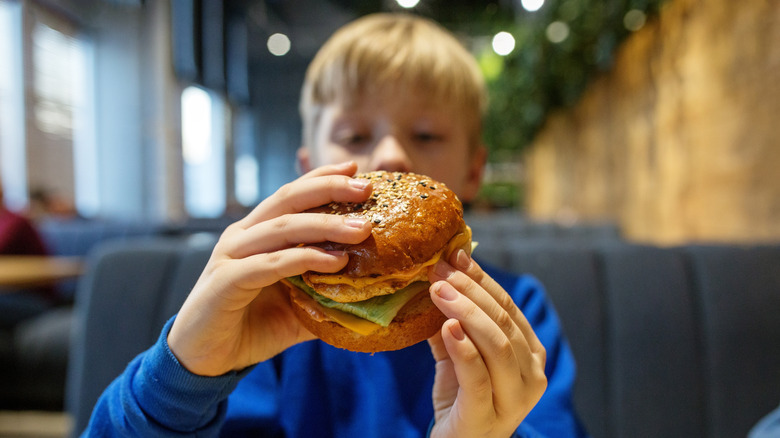 A child eats a burger in a restaurant
