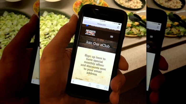 Hand holding phone showing Hoss's eClub