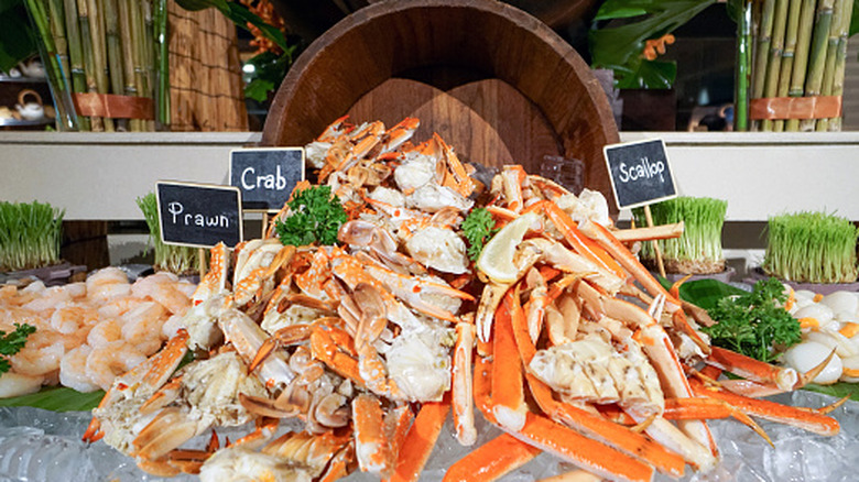 A pile of cold seafood at a seafood buffet, with various labels displaying each food
