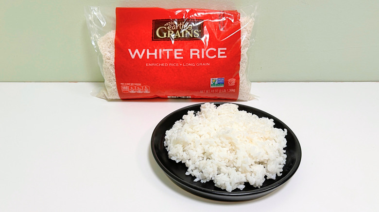 A bag of Earthly Grains Long Grain White Rice next to a black plate of rice