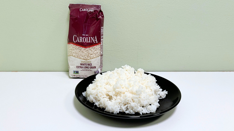 A bag of Carolina Enriched Extra Long Grain White Rice next to a black plate of rice