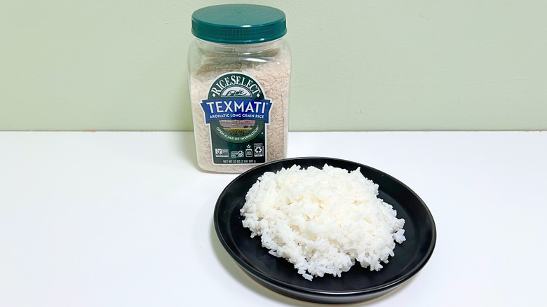 A container of Rice Select Texmati Long Grain Rice next to a black plate of rice