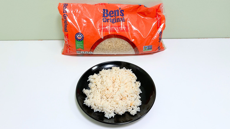 A bag of Ben's Original Long Grain White Rice next to a black plate of rice