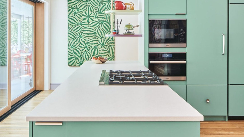 A modern kitchen with tall, mint-green cabinets and a matching island