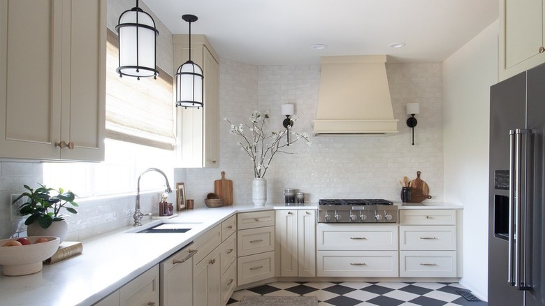 A monochrome kitchen with silver appliances and a checkerboard floor