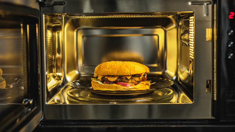 A burger is seen inside a modern microwave