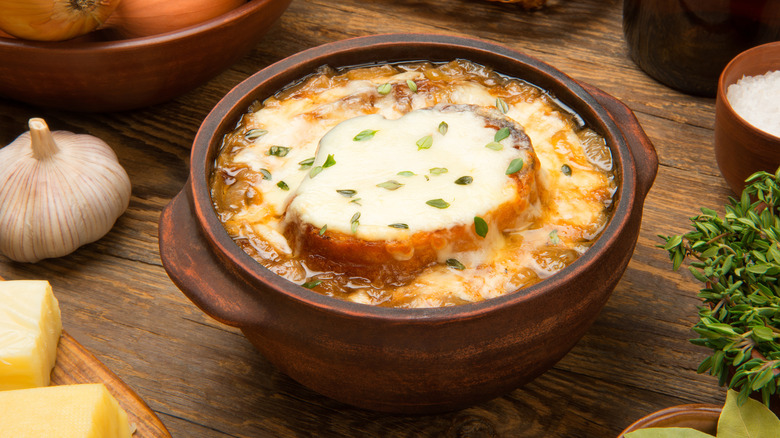 A bowl of French onion soup is displayed next to its ingredients